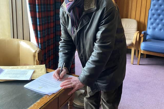 Andy Mathieson, club secretary, signs documents agreeing to the refurbishment of the building.