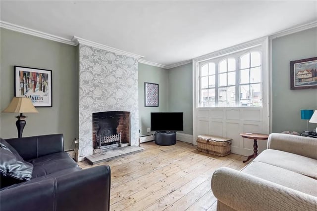 The large living room features an open fireplace and arched sash windows