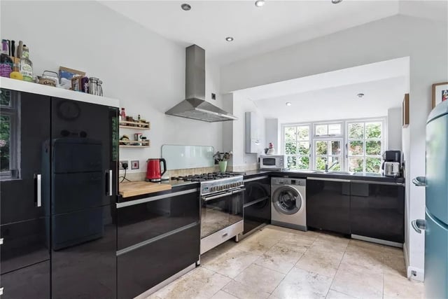The kitchen is fitted with gloss units, has a travertine tiled floor and space for appliances