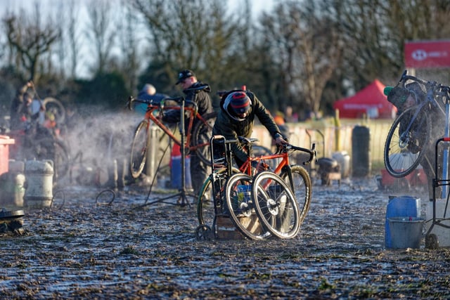 Riders clean their bikes after a day of mud-splattered action