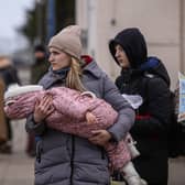 A woman who fled war-town Ukraine  holds a baby as she walks to board a train to transport them to Przemysl main train station after crossing the Polish Ukrainian border. (Photo by Omar Marques/Getty Images)