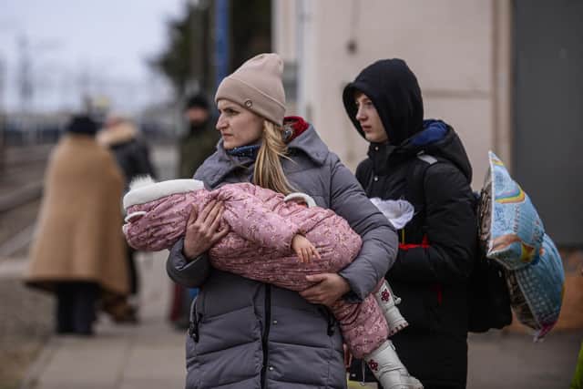 A woman who fled war-town Ukraine  holds a baby as she walks to board a train to transport them to Przemysl main train station after crossing the Polish Ukrainian border. (Photo by Omar Marques/Getty Images)
