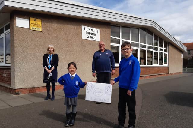 From left: St Marie's RC Primary headteacher Mary Caldwell with janitor George Tullis who retired on Wednesday along with pupils Charlene Ho (5) and Kenzi Mackie (10) with a special poster to mark George's departure.
