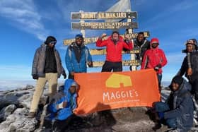 Don pictured at the top of Kilimanjaro with his banner for Maggie's Fife, along with the guides and porters on the trek.
