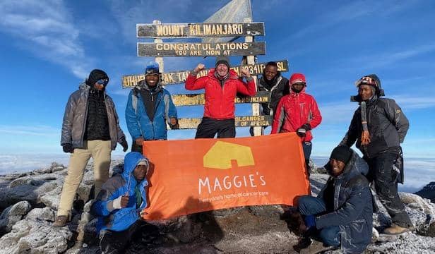 Don pictured at the top of Kilimanjaro with his banner for Maggie's Fife, along with the guides and porters on the trek.