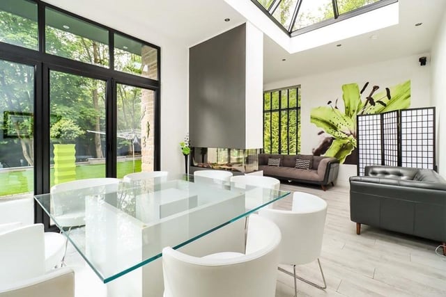 Family room with dual aspect feature gas fire, atrium glazed roof, and windows overlooking the rear garden.