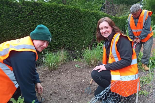 Volunteers Chloe & William watch Activities Co-ordinator Fiona Young (centre) plant the first new flax at Silverburn Park, Leven.