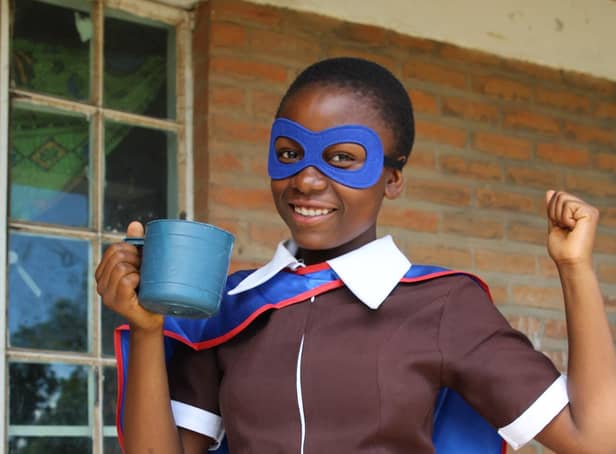 Upile with the daily mug of vitamin-enriched porridge that she receives from Mary’s Meals.