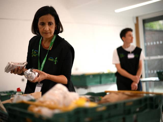 A member of staff sorts through food items inside a foodbank (Photo by DANIEL LEAL/AFP via Getty Images)
