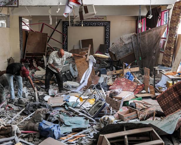 A man and a boy inspect items to be salvaged from a heavily damaged room at a schoo (Photo by -/AFP via Getty Images)