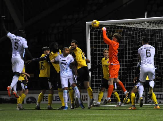 Queen's goalkeeper Charlie Cowie punches clear at a corner.