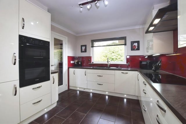 Kitchen with ample base and wall mounted cupboards, contrasting worktops, integrated appliances, underfloor heating, underlighting, and a Belfast sink unit.