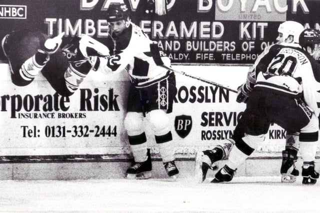 An opposing player falls over the boards in a game circa 1993. The Fife skater is Doug Marsden.