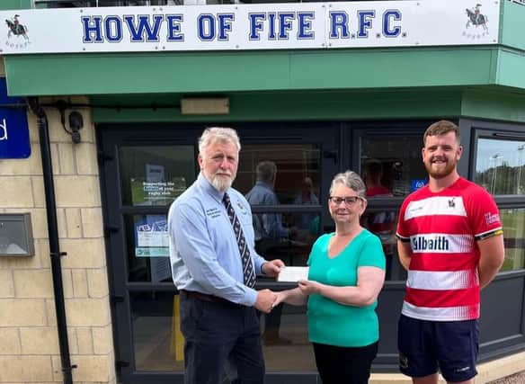 Howe of Fife Club president Gordon Thomson presents the cheque to lotto winner Isabel Poole, watched by senior player Jake Douglas.
