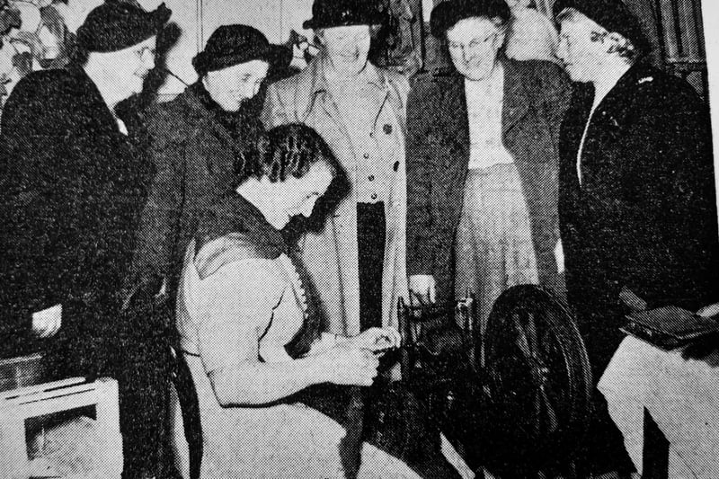 Mrs J. Page, James Grove, Kirkcaldy, watched by visitors to the annual Handicrafts Exhibition at the YMCA, gives a demonstration on a spinning wheel.