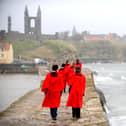 Students from the University of St Andrews walk along the harbour wall wearing their famous red gowns (Pic: Jane Barlow)