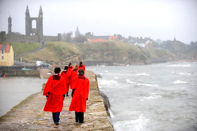 Students from the University of St Andrews walk along the harbour wall wearing their famous red gowns (Pic: Jane Barlow)