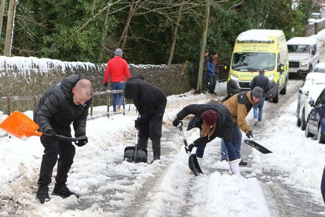 Residents from Victoria Park Road, Buxton clear snow to allow an ambulance up the steep hill