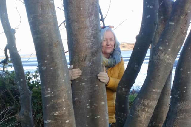 Linda is pictured hugging trees for their vibrant energy, just like the earth angel Kirsty in her new book, The E.A.R.T.H Gang.