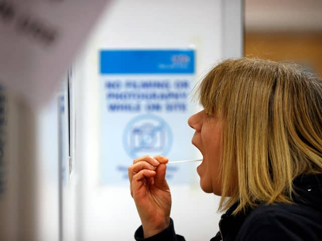A woman uses a swab to take a sample from her mouth at a NHS Test and Trace Covid-19 testing unit. Photo by ADRIAN DENNIS/AFP via Getty Images