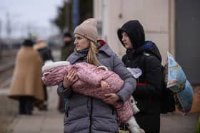 A woman who has fled war-town Ukraine  holds a baby as she walks to board a train to transport them to Przemysl main train station after crossing the Polish Ukrainian border  (Photo by Omar Marques/Getty Images)