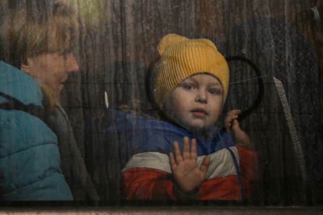 A child greets from the window of a bus after crossing the Ukrainian border with Poland at the Medyka border crossing. (Pic: LOUISA GOULIAMAKI/AFP via Getty Images)