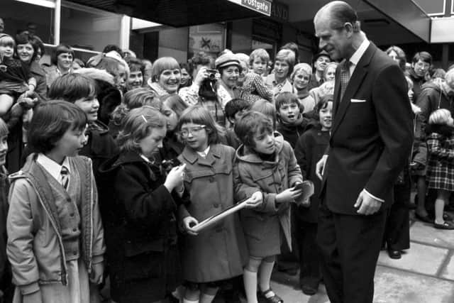 October 1976: Prince Philip  stops to chat with a little girl whose camera isn't working when he visits the Kingdom shopping centre in Glenrothes.