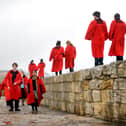 Students from the University of St Andrews walk along the harbour wall wearing their infamous red gowns.(Pic: TSPL)