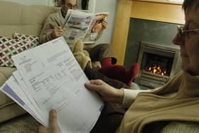Aly woman looks at her gas bill as both she and her husband sit in front of their gas fire keeping warm in the cold (Pic: TSPL)
