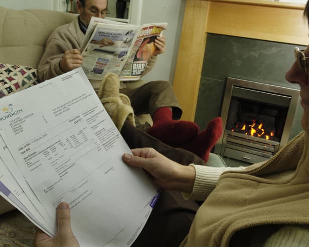 Aly woman looks at her gas bill as both she and her husband sit in front of their gas fire keeping warm in the cold (Pic: TSPL)