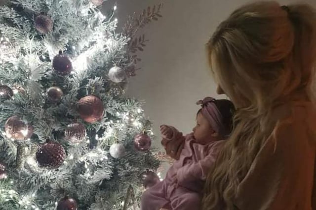 A little angel takes a closer look at her first Christmas tree.