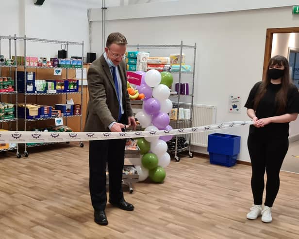 . John Bayne cutting the ribbon with help from Jade Hutton from the pantry team.