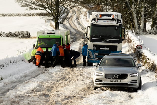 People help to push an Asda delivery van stuck on the A515 on Saturday.