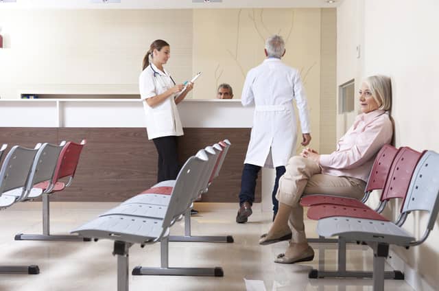 Doctors and patient discussing in hospital waiting room. (Shutterstock)