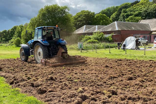 Tractor ploughing an area behind the mill in preparation for more flax planting