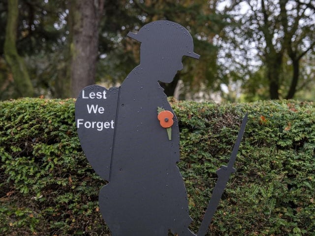 Two silhouetted figures stand in silent tribute.
