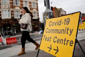 A pedestrian walks past a directional sign for a Covid-19 test centre. Photo by TOLGA AKMEN/AFP via Getty Images