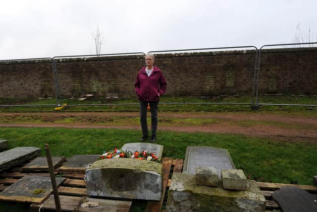 Marion Wallace pictured in Auchtertool Cemetery where headstones have been placed on the ground because of an unsafe wall next to where they originally stood. Pic: Fife Photo Agency