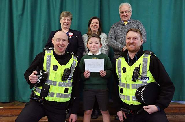 Falkland Primary School pupil Henry Bull (10), who won the competition, with Sergeant Ewan Pearce (left) and Constable Graeme Whittaker. Pictured from left at the back are Elaine Braildsford (Cupar Tesco community champion, who handed over a box of games to Henry), head teacher Jan Adair and local Fife Councillor David McDiarmid.