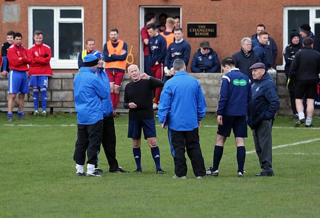The referee speaking to officials as he calls off the match. Picture by Dave Scott.