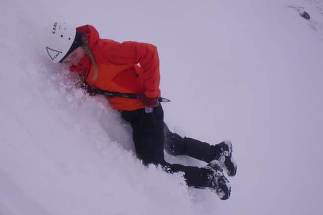 One of the students learns to use an ice-axe to halt a slide on a snowy slope.