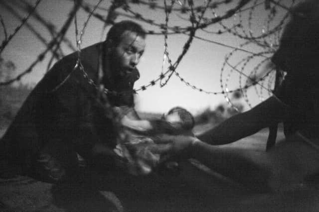 The winning image by Warren Richardson - a powerful picture featuring refugees crossing through border fencing from Serbia into Hungary.