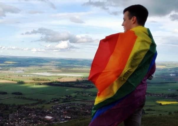 Stuart Russell, with the LBGT rainbow flag, looks out over Fife from on top of the Lomond Hills.