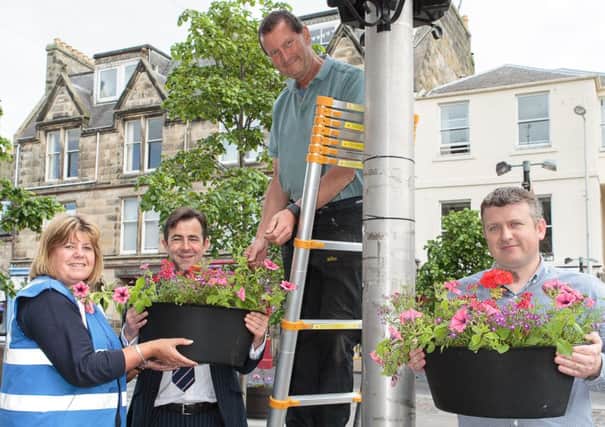 BID St Andrews Chair Alistair Lang (second left) and St Andrews Links Trust Technical Services & Compliance Manager Tony Toshney (right) help St Andrews in Bloom Chair Barbara Boyd and Treasurer Henry Paul put up planters on Market St.