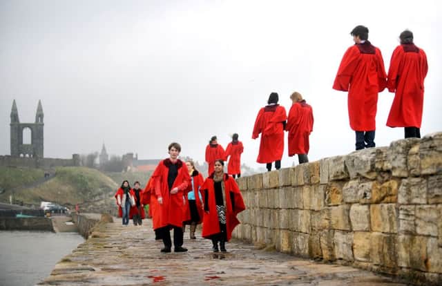 Picture by JANE BARLOW. 19th April 2012. Students from the University of St Andrews walk along the harbour wall wearing their infamous red gowns.