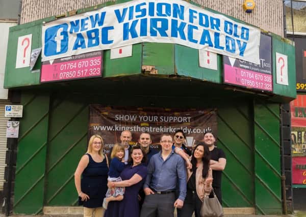 Forging ahead: Grant (centre) with his supporters and the new banner now pinned above the entrance to the old cinema he wants to bring back into use