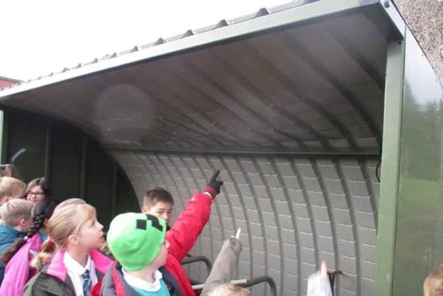 Pupils point to the damage of the shelter's roof.