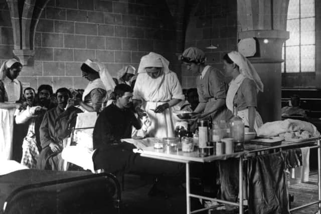 Nurses assisted by a blue capped orderly doing dressings in a field hospital set up by Elsie Inglis during the First World War.