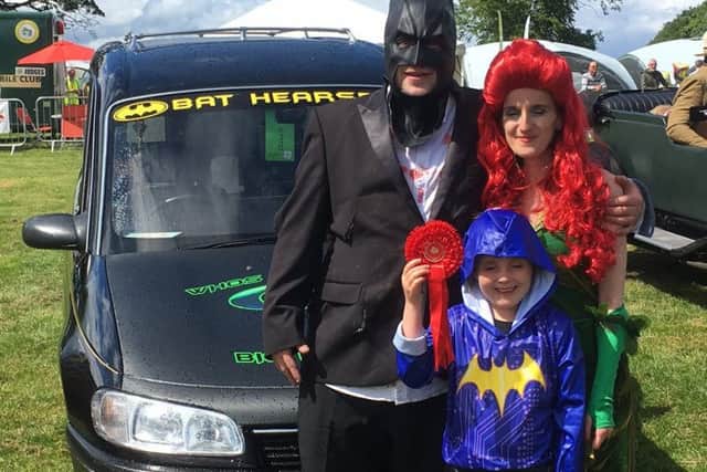 Mark Lumsden with his wife Louise and daughter Emma in front of the Bart-Hearse. Pictures: SWNS