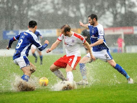 Greig Spence splashes his way into a challenge with two Stranraer players. Pic: Fife Photo Agency